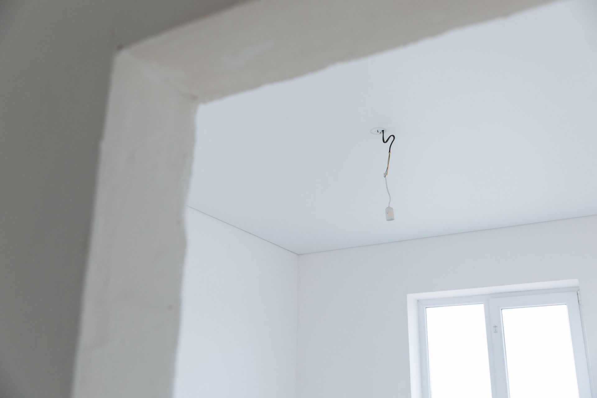Bright white interior room with exposed electrical wiring and natural light.